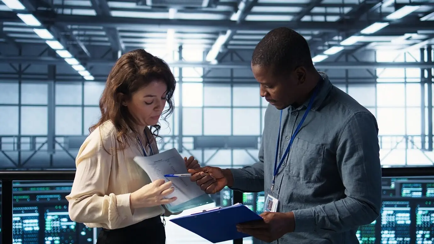 Team von Aufsichtskräften eines Rechenzentrums beim Lesen von Papierunterlagen